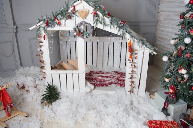 Foto fiaba di natale. fondo interno della casa del piccolo giocattolo di legno carino. decorazioni per le vacanze di natale. studio di decorazioni festive. albero di natale e decorazioni natalizie per la stanza dei giochi.