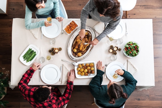 Cena di natale in famiglia vista dall'alto donna caucasica matura che intaglia il pollo arrosto di natale holiday