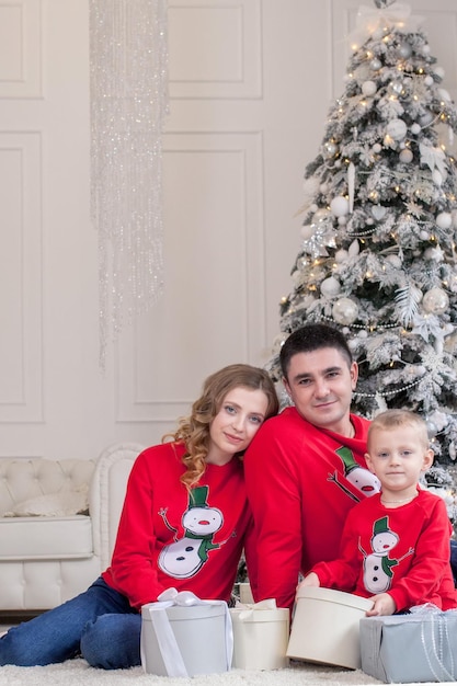 Christmas Family Happiness Portrait of dad son sitting on a floor at home near the Christmas tree all are smiling