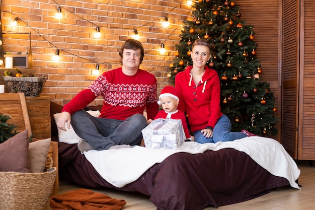 Christmas family. Happy mom, dad and little child near Christmas tree. Enjoying love hugs, holidays people. Togetherness concept