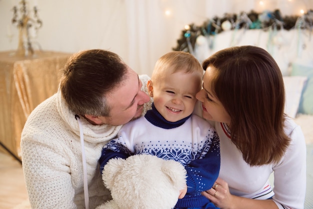 Christmas family. Happy mom, dad and little son lying on the bed