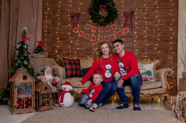 Christmas Family Portrait in Xmas Tree Interior Lights, Happy New Year with Children. The concept of family winter holiday.