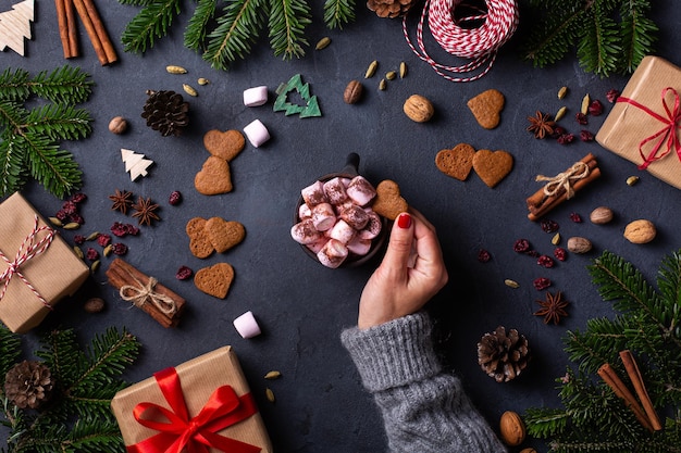 Christmas female hands with gift boxes and cup of cocoa