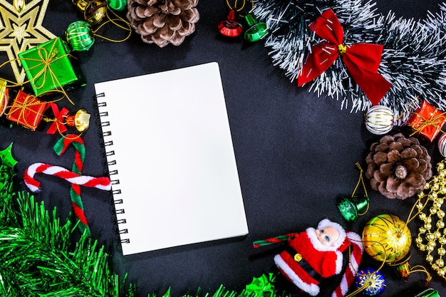 Christmas festive decorations with empty notebook and pencil on black paper background