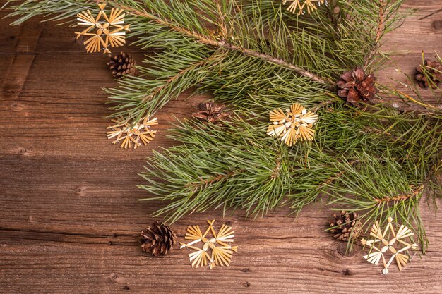 Photo christmas festive old wooden background. zero waste christmas decor concept. fresh evergreen pine branches and straw snowflakes, flat lay