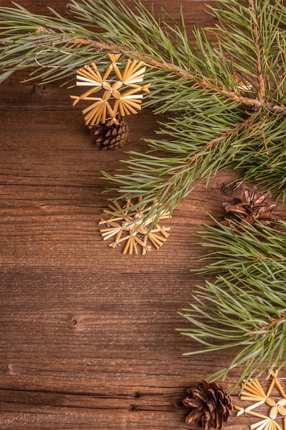 Christmas festive old wooden background. Zero waste Christmas decor concept. Fresh evergreen pine branches and straw snowflakes, flat lay