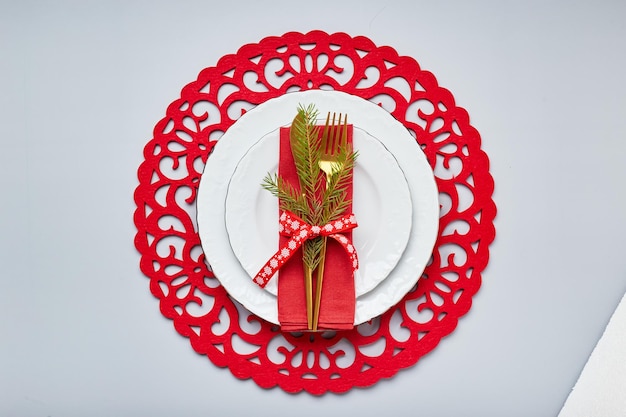 사진 흰색 접시와 금색 칼붙이 빨간색 린넨 냅킨 전나무 가지가 있는 크리스마스 축제 테이블 설정