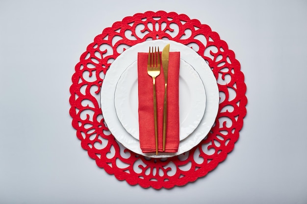 Christmas festive table setting with white plates and gold cutlery red linen napkin fir branches red