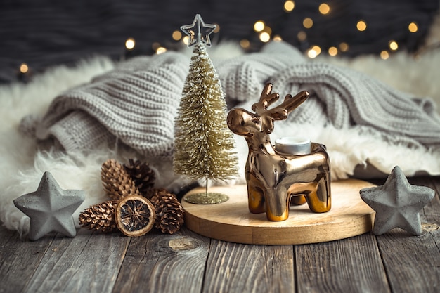 Christmas festive table with toy deer, blurred table with golden lights and candles