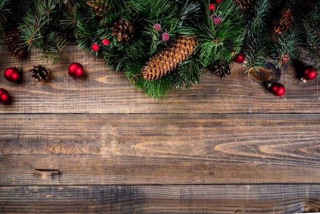 Christmas fir tree branch with pine cones and decorations on wooden table. Top view,  copyspace.