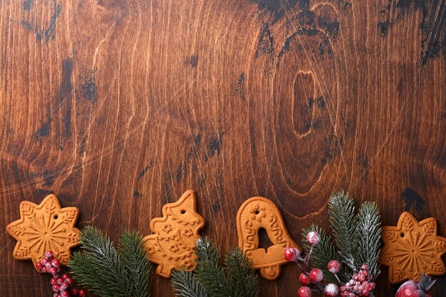 Christmas fir tree branches, Christmas balls, Christmas gingerbread, gift box, wooden snowflakes and stars on old wooden background for xmas greetings. Top view, copy space. Christmas greeting card.