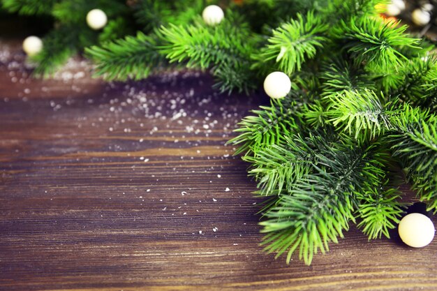 Christmas fir tree branches with lights on wooden table