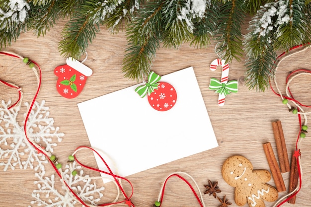 Christmas fir tree, gingerbread cookies and card for copy space on wooden table