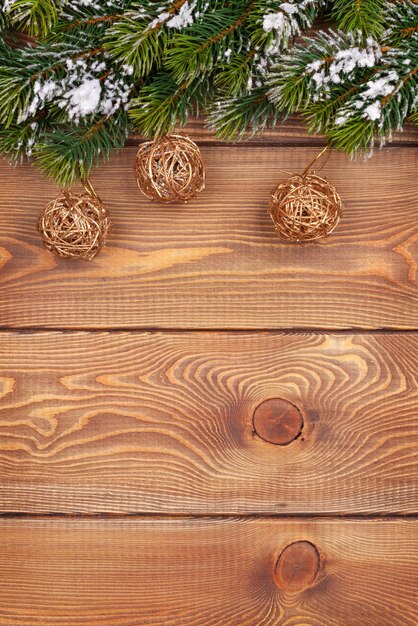 Фото Рождественская елка со снегом и безделушками на деревенской деревянной доске