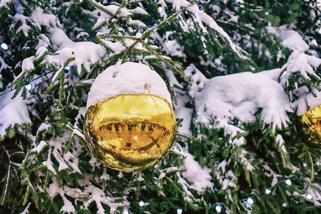 白い雪と伝統的な黄金のボールの冬の背景を持つクリスマスのモミの木