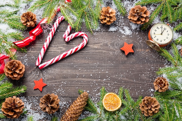 Christmas fir trees in snow with cones, candy canes, vintage clock