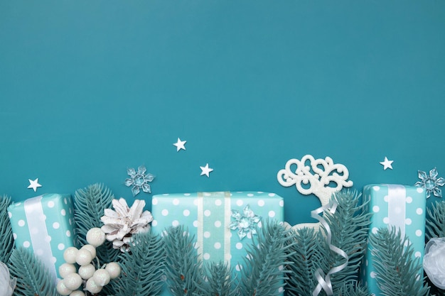 Christmas flat lay background with gifts berries and pine on turquoise backdrop with copy space
