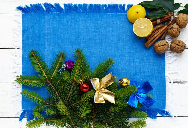 Christmas flat lay. Branch spruce, decorations, nuts, cinnamon, lemon on blue napkin