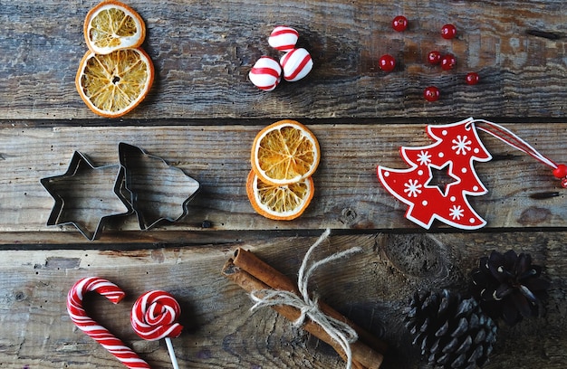Фото Рождественская плоская планировка домашнего декора сухие апельсины конфеты с корицей игрушки на деревенском деревянном фоне вид сверху уютная зимняя домашняя сцена
