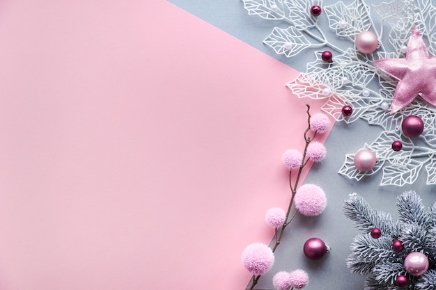 クリスマスフラットは、コピースペースとピンクとシルバーの2色の背景に横たわっていた。光沢のある幾何学的な葉と柔らかい繊維のつまらないもの、散りばめられたガラスのクリスマスボールが飾られた装飾的な白い冬の小枝。