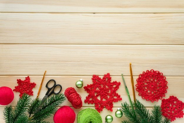 Christmas flat lay of items for needlework. Knitted snowflakes, threads and hooks on wooden