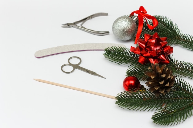 Christmas flat lay nail salon on white with christmas tree and red ornaments.