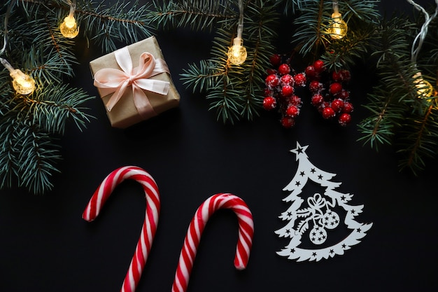 Christmas flat lay with firtree branches red berries gift candy canes and wooden Christmas tree