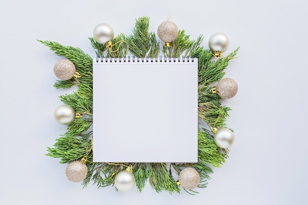 Christmas flat lay with paper blank, baubles, fir branches on white