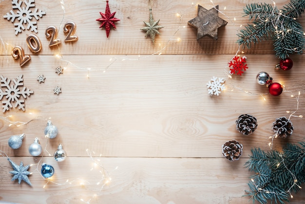 Christmas flat lay with pine tree branches, candy canes, Christmas baubles and golden 2022 numbers