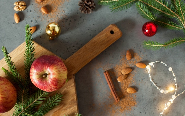 Flatlay natalizio di mele, noci, cannella e rami di alberi. il concetto di natale e capodanno. biglietto d'auguri.