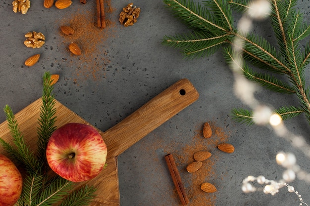 Flatlay natalizio di mele, noci, cannella e rami di alberi. il concetto di natale e capodanno. biglietto d'auguri.