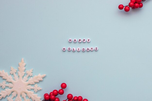 Photo christmas flatlay snowflakes and spruce branch on blue background and text happy holidays