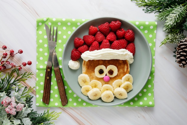 クリスマスフード-子供のためのラズベリーとバナナのサンタパンケーキ。