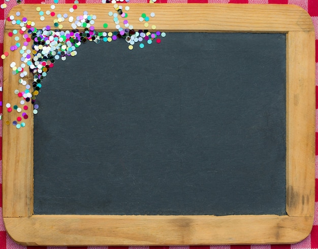 Christmas frame of confetti on blackboard blank. Winter holidays concept