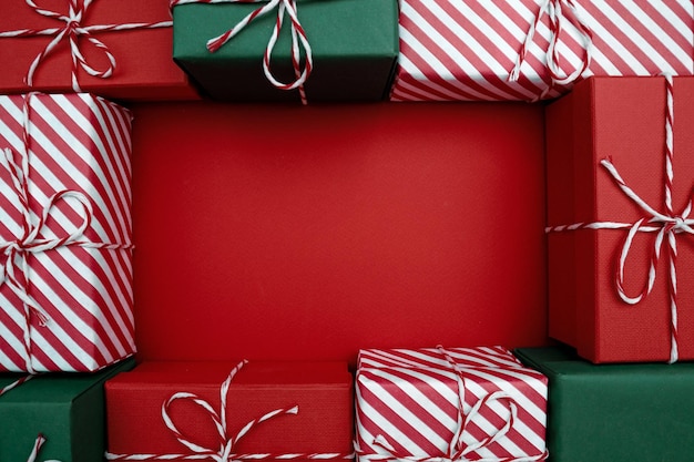 Рождественская рамка, украшенная праздничными подарками на красном фоне, плоская планировка