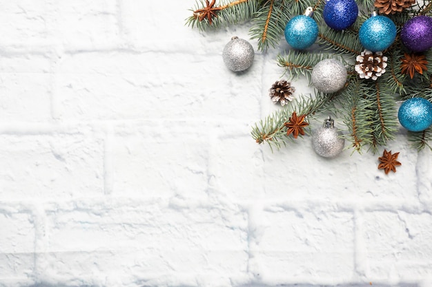 モミで作られたクリスマスフレーム、明るいレンガの背景に銀と青のクリスマスツリーの装飾。コピースペース。フラット横たわっていた。