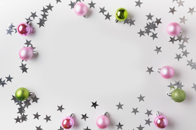 Фото Рамка рождества серебряных и розовых шариков на белизне. вид сверху. рождественский фон для пожеланий. поздравительная открытка