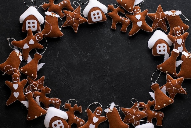 Christmas frame of toy gingerbread cookies on a black background, top view.