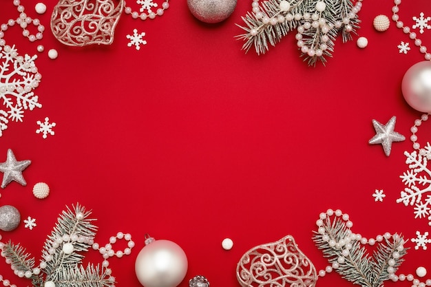 Christmas frame of white ornaments on red background with copy space.