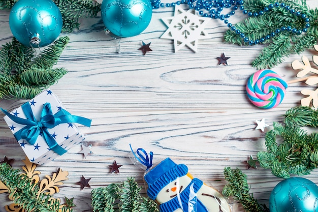 Christmas frame with copy space background, decorated with fir tree branches, blue balls, present, snowman cookie