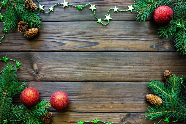 Christmas frame with fir branches cones on a dark wooden table top view with space for text