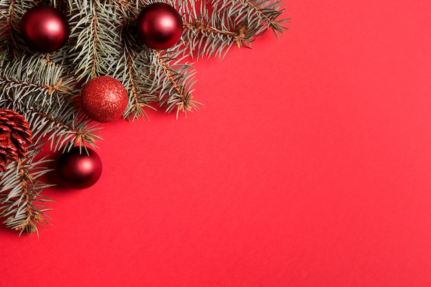 Christmas frame with fir branches, red balls on red background. 