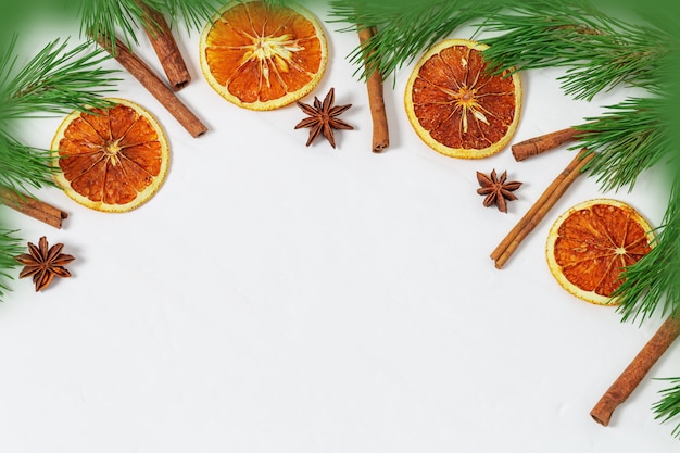 Рождественская рамка с сосновыми ветками и специями, корицей, анисом и нарезанными апельсинами для фона
