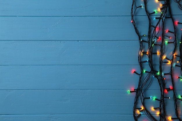 Christmas garland lights on blue background, copy space