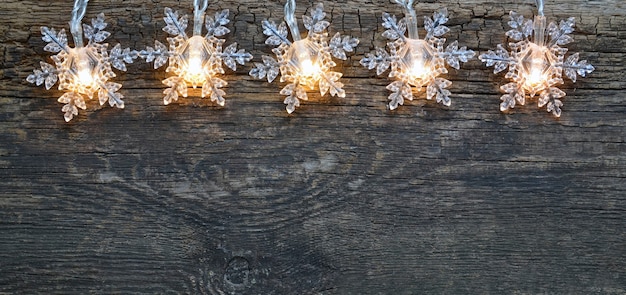 Christmas garland lights border on old wooden table Winter festive decoration with copy space