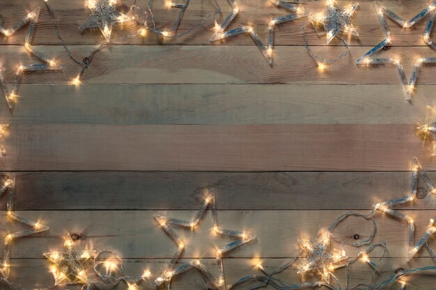 Christmas garland star glowing on wooden old background. Copy space, flat lay