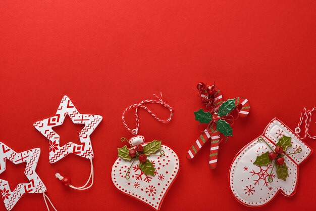 クリスマスの花輪、おもちゃ、プレゼントボックス。新年またはクリスマスフラットレイトップビュークリスマスの休日のお祝いの装飾赤い紙の背景とコピースペース。テンプレートモックアップグリーティングカードのテキストデザイン