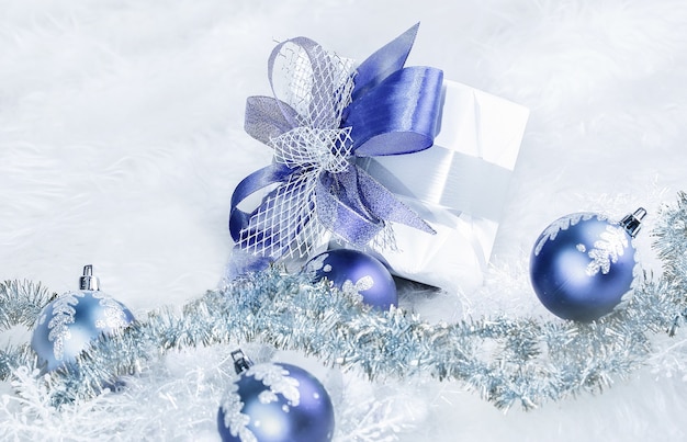 お祝いの白い背景の上のクリスマスプレゼントと青いクリスマスボール。コピースペースの写真