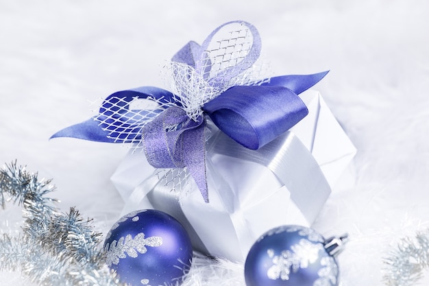 Christmas gift and blue Christmas balls on a festive white