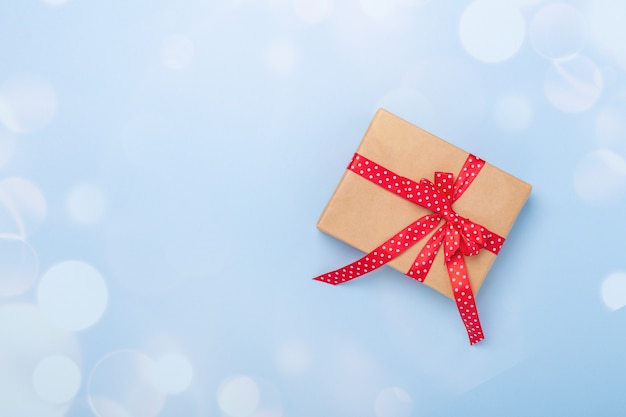 Рождественская подарочная коробка и боке украшения на синем фоне